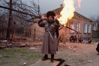 Чеченец совершает намаз. На фоне горит газовая труба. Чечня, 1995 год