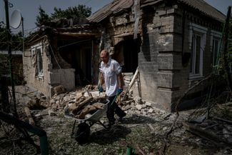 Житель Никополя убирает двор после обстрела города