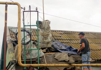 Рабочие достают обломки российской ракеты через дыру в крыше дома в Одессе