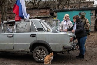 Мобильный избирательный участок на досрочном голосовании в Донецке. Члены избирательной комиссии готовятся к приему избирателей в присутствии российского военнослужащего