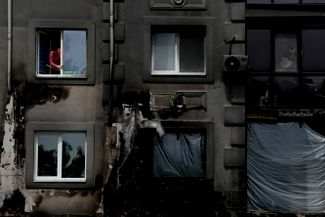 Женщина моет окна своего дома в Буче. После освобождения от оккупации город возвращается к обычной жизни.