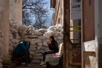 Волонтеры курят у заграждения из мешков с песком. Николаев, 28 марта 2022 года<br>