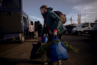 A bus stop in Staryi Saltiv. Local resident Sasha takes a Christmas tree home. December 30, 2023.