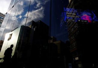 Здание бизнес-центра в Токио, в отражении — динамика индекса Nikkei. 23 января 2024 года