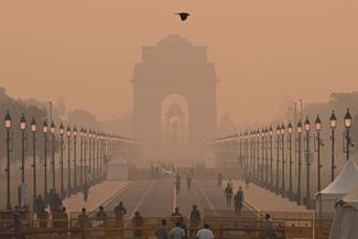 Люди идут в сторону Ворот Индии во время плотного смога 25 октября 2022 года. Качество воздуха опустилось тогда до рекордных отметок, что совпало с празднованием фестиваля Дивали. Несмотря на праздник, правительством был введен запрет на использование петард в районе Нью-Дели