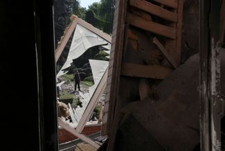 Прохожий смотрит на разрушенное здание жилищно-коммунального колледжа