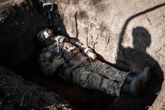 Боец ВСУ лежит в траншее во время стрельбы из противотанкового гранатомета по российским позициям