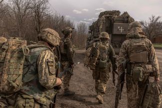 Украинские пехотинцы 23-й механизированной бригады идут к боевой бронированной машине MaxxPro, которая направляется к линии фронта 