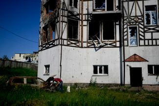Мужчина осматривает свою машину после бомбардировок в селе Мостище