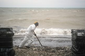 Cleaning up petroleum products that washed ashore after a fire at an oil station. April 25, 2026