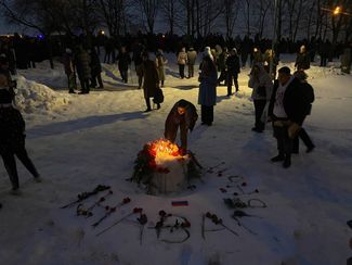 Mourners light candles at a makeshift memorial outside the cemetery. “Navalny” is written in flowers around the memorial.