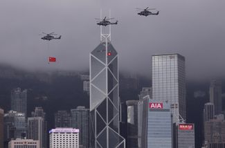 Вертолеты пролетают мимо здания банка Bank of China с флагами КНР и САР Гонконг в праздник 24-й годовщины передачи Гонконга Китаю. 1 июля 2021 года