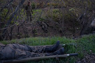 Украинский военный осматривает тела российских солдат, найденные у дороги между Купянском и Купянском-Узловым