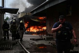 Украинские пожарные тушат огонь на центральном рынке Славянска. В результате российского обстрела, по сообщению местных властей, погибли как минимум двое горожан, еще семеро ранены