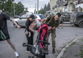 Раненый солдат помогает раненой жительнице Краматорска и ее ребенку 