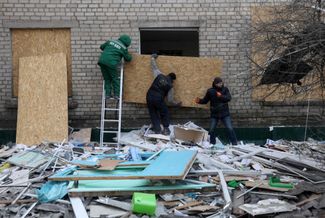 Сотрудники коммунальной службы закрывают фанерой разбитые окна больницы