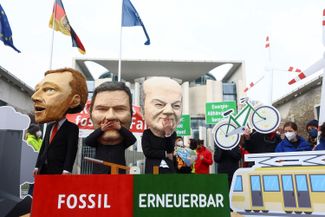 Демонстранты в масках канцлера Олафа Шольца, министра финансов Кристиана Линднера и министра экономики Роберта Хабека на митинге за «зеленый переход» и освобождение от сырьевой зависимости от России. Берлин, 6 апреля 2022 года.<br><br>