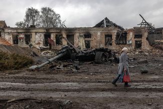 Жительница города Тростянец, отвоеванного украинскими военными, на фоне уничтоженной самоходной артиллерийской установки