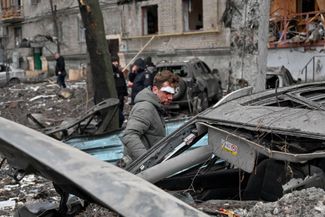 Харьковчанин, пострадавший в результате ракетного удара, осматривает свой уничтоженный ВС РФ автомобиль. 