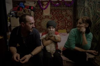 Dmytro, Oksana, and their son Mykyta in the only room of their rural house. Apart from the living room, the house has only a small kitchen. January 1, 2023.