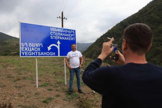 Азербайджанцы фотографируются у дорожного знака на дороге между Лачином и Шушей на территории Нагорного Карабаха. 1 октября 2023 года
