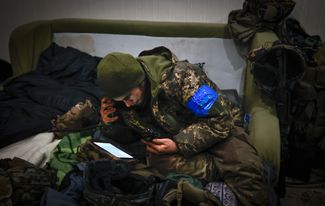 Украинский военный изучает ситуацию на линии фронта вокруг Соледара, находясь в убежище