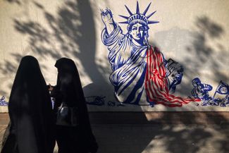 Жительницы Тегерана на фоне антиамериканского граффити на стене здания, в котором ранее располагалось посольство США в Иране. 14 октября 2023 года