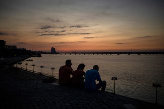 Семья смотрит на закат на берегу Днепра