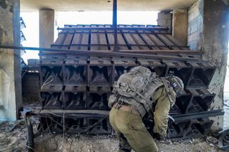 Израильский военнослужащий рядом с установкой, предположительно использовавшейся боевиками «Бригады Аль-Кудс» для запуска ракет, 6 ноября 2023 года