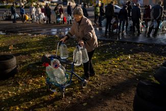 Жительница Николаева везет домой тележку с бутылками питьевой воды