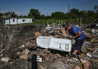 Житель поселка Чаплино забирает остатки еды из холодильника среди руин своего дома. Он был разрушен ракетным ударом российских войск по Чаплино, как и несколько других жилых домов