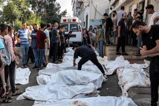 Палестинцы ищут погибших родственников возле морга больницы Аль-Шифа в городе Газа. 12 октября 2023 года