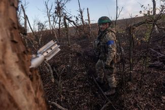 Украинский солдат смотрит на минометный снаряд, застрявший в стволе дерева