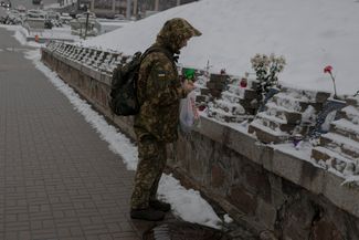 Украинский военный ставит свечу возле памятника «Небесной сотне» в Киеве. Он был установлен в столице Украины. Мемориал сделан в виде казацкого креста — одного из символов свободы Украины
