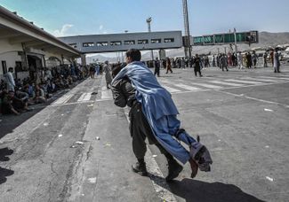 Волонтер и раненый в кабульском аэропорту. Тысячи людей осаждают летное поле, пытаясь покинуть страну после захвата власти талибами. 16 августа 2021 года
