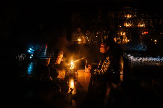 Центр Киева. Люди сидят в баре при свечах после того, как 16 декабря российские военные нанесли удары по энергетической инфраструктуре города