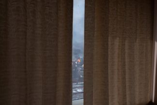 Вид из окна на загоревшийся после обстрела дом в Мариуполе. 12 марта 2022 года