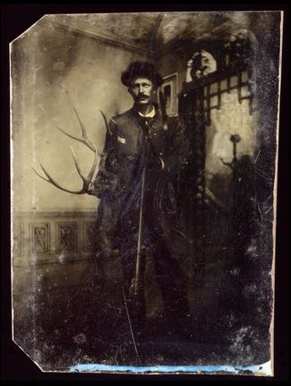 Портрет охотника с ружьем и оленьими рогами в руках