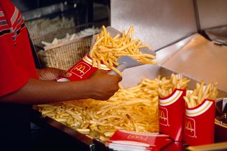 Сотрудник чикагского «Макдоналдса» готовит заказ на картофель фри, 12 июля 1990 года