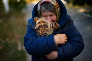 Женщина согревает свою собаку. Жители Ковшаровки около трех недель жили без газа, электричества и воды. 