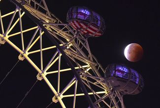 Луна, частично скрытая за земной тенью, и колесо обозрения «Лондонский глаз»