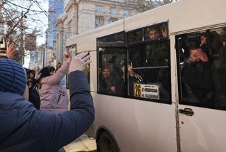 Women wave to men departing from a mobilization point that was established at a local middle school by the conscription office for the Kalininsky, Kyivsky, and Voroshilovsky districts of Donetsk. February 23, 2022