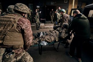 Бойцы ВСУ несут раненого товарища в военный госпиталь в Бахмуте. Город уже несколько месяцев пытаются взять отряды ЧВК Вагнера, он находится под постоянными обстрелами