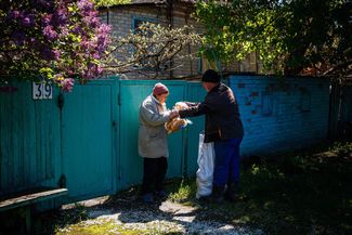 44-летний Александр Ващенко делится с соседкой хлебом, полученным в рамках гуманитарной помощи.