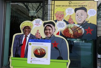 Изображения Трампа и Ким Чен Ына на входе в один из ресторанов в Сингапуре