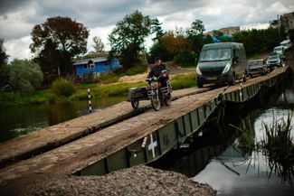 Гражданские и военные автомобили пересекают Северский Донец по временному мосту в Изюме