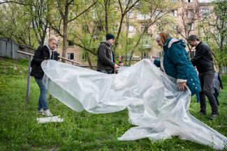 Люди готовят пластиковые шторы, чтобы закрыть окна, оставшиеся без стекол после российского ракетного удара