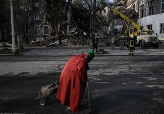 Жительница Краматорска идет мимо разрушенного здания