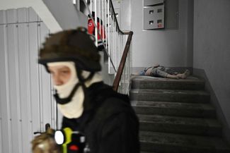 Украинский спасатель в подъезде жилого дома в Херсоне. На лестничном пролете лежит тело одного из погибших мирных жителей