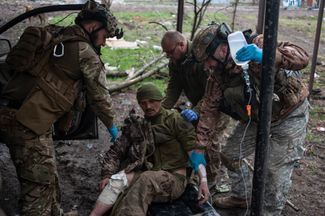 Украинские военные оказывают первую медицинскую помощь сослуживцу, раненному в боях за Бахмут